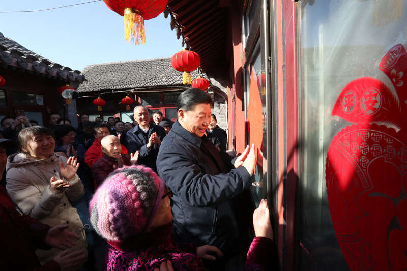 2019年2月1日上午，習(xí)近平在北京前門(mén)東區(qū)草廠(chǎng)四條胡同32號(hào)院，高興地拿起一幅“?！弊?，親自貼到門(mén)上，給這里的老街坊們拜年。新華社記者 鞠鵬 攝